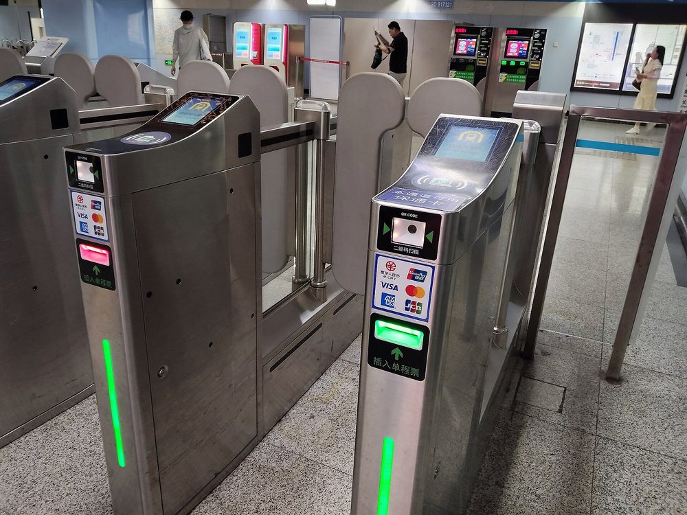 Close-up of smartphone scanning dynamic Alipay transport QR code at sleek subway turnstile glass reader