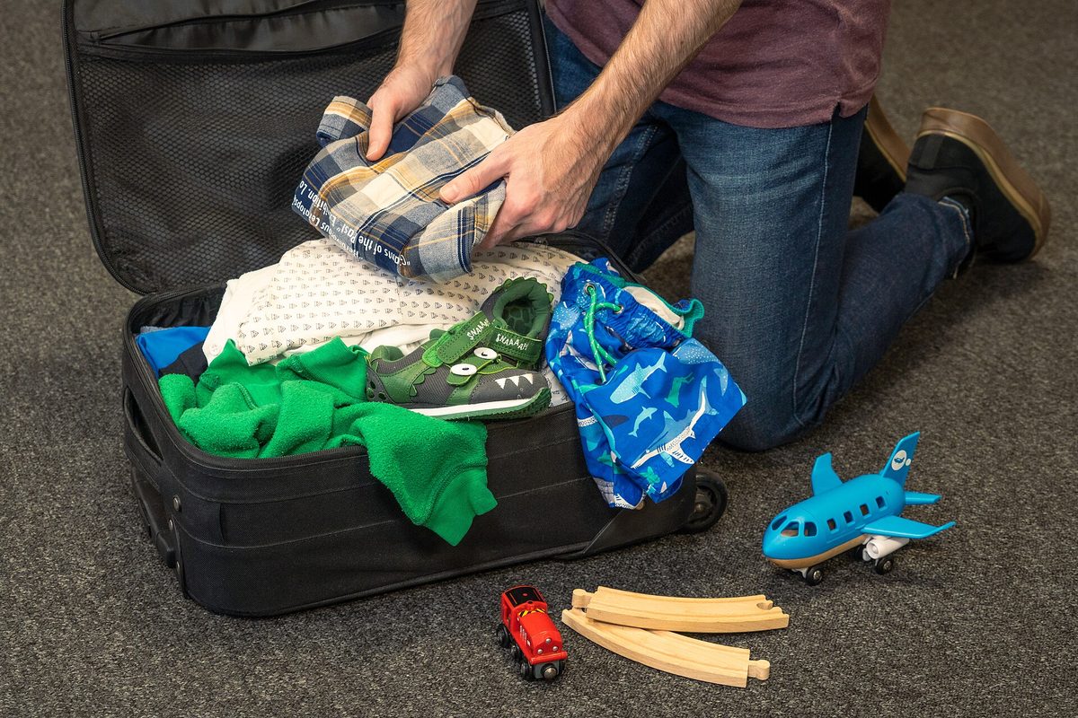 Neatly organized travel packing flat lay with dual-prong chargers, travel medicines, and passport on clean surface