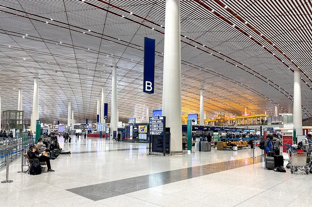 Moderne Abflughalle eines chinesischen Großflughafens mit digitalen Check-in-Kiosken und Passkontrollschaltern