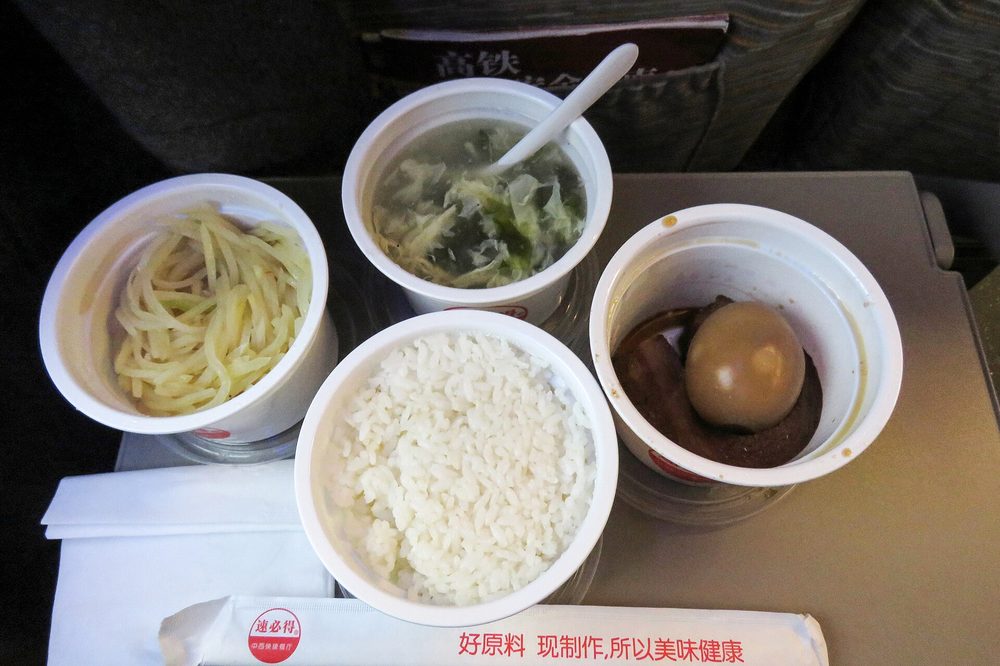 Hôtesse de bord chinoise apportant un repas chaud commandé sur application au siège d'un voyageur en TGV