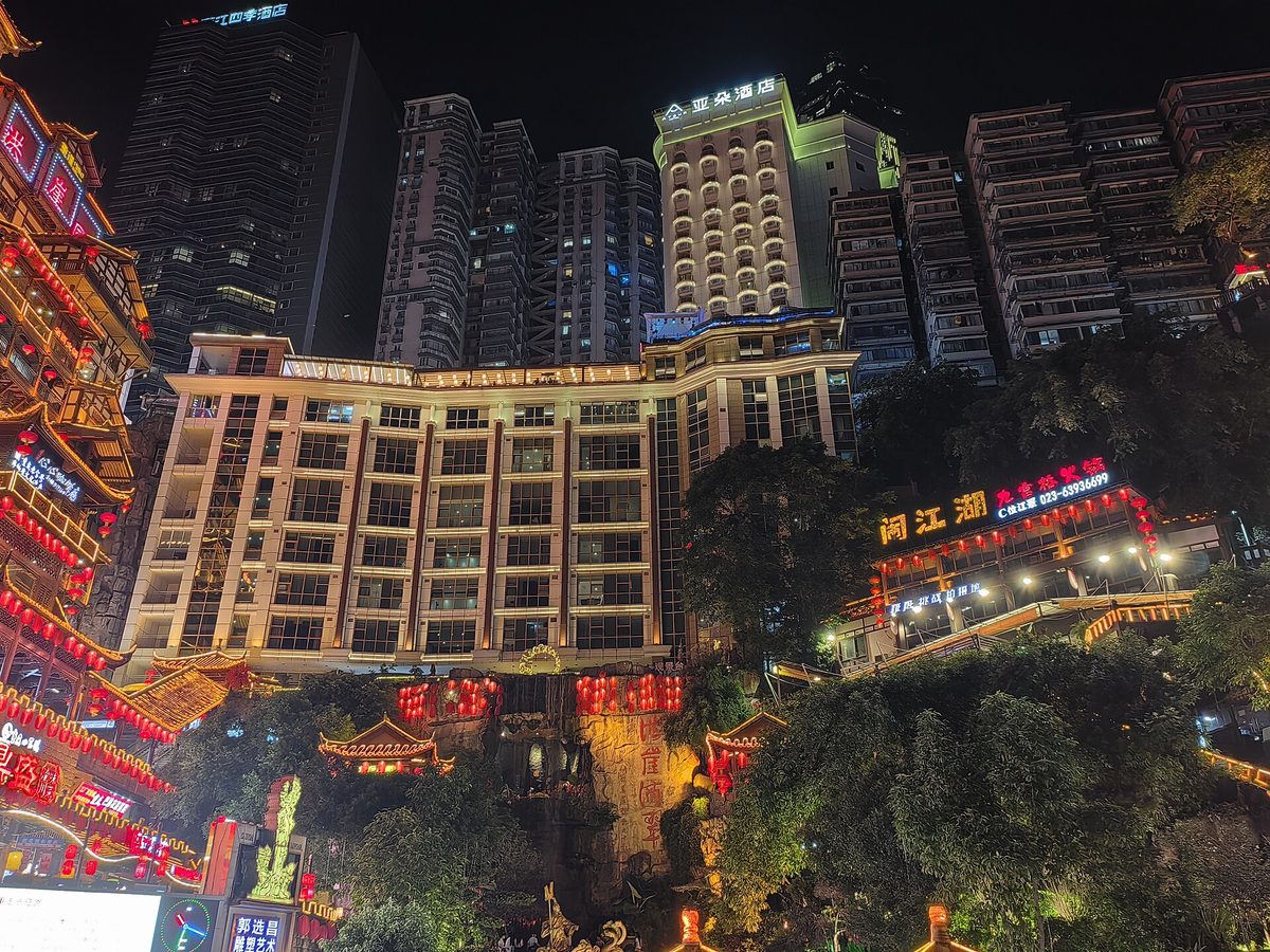 Dramatic evening view of the illuminated multi-tier Hongyadong stilt house complex clinging to the cliffside in Chongqing