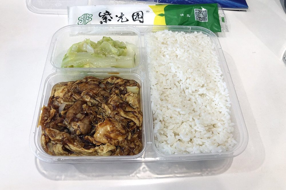 Repartidor de Meituan con chaleco amarillo y moto eléctrica entregando comida en China