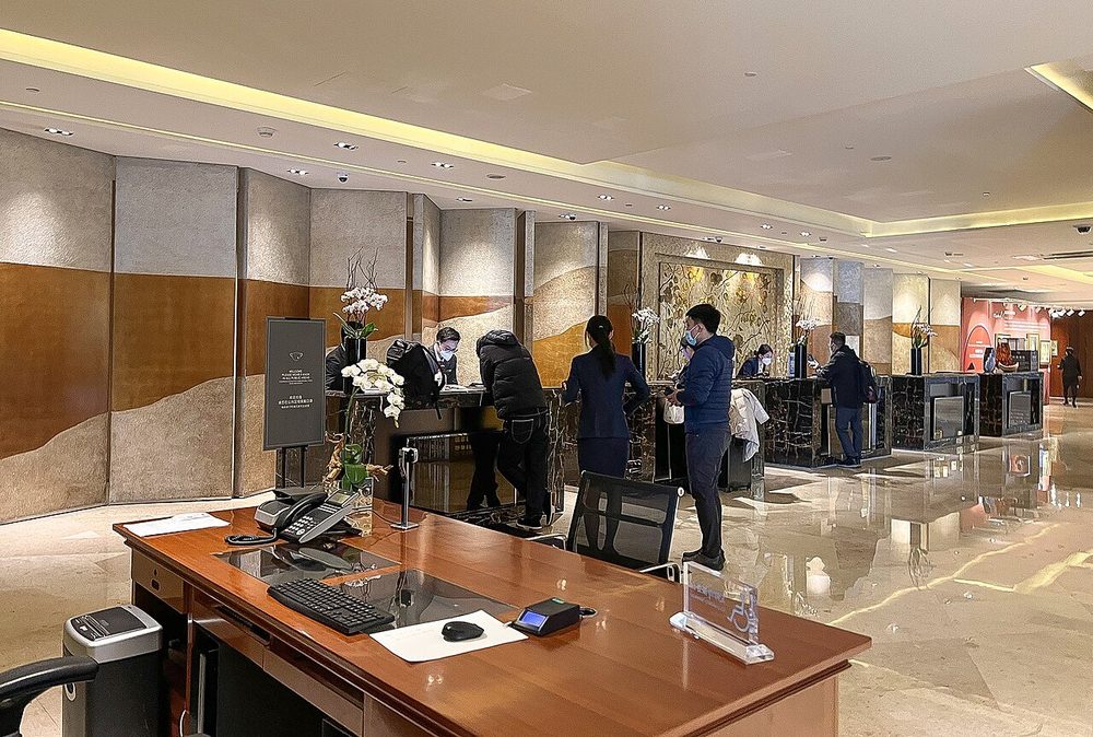 Großzügige Rezeption mit Marmortheke und traditioneller chinesischer Kunstwand in einem Hotel in Peking