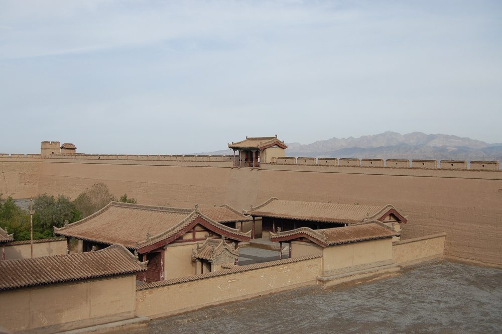 Towering sand dunes of Singing Sand Dunes reflecting in the crescent-shaped spring oasis lake in Dunhuang at golden hour