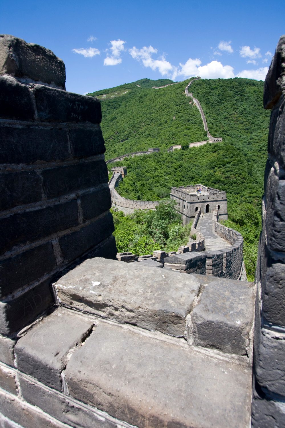 Spectacular view of Mutianyu Great Wall winding over steep green forested mountain ridges with restored watchtowers
