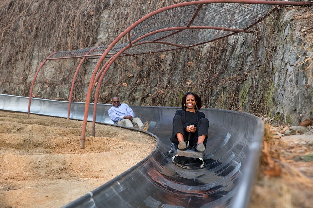 Adventurous traveler riding the wheeled toboggan cart down the curving stainless steel track from Mutianyu Great Wall