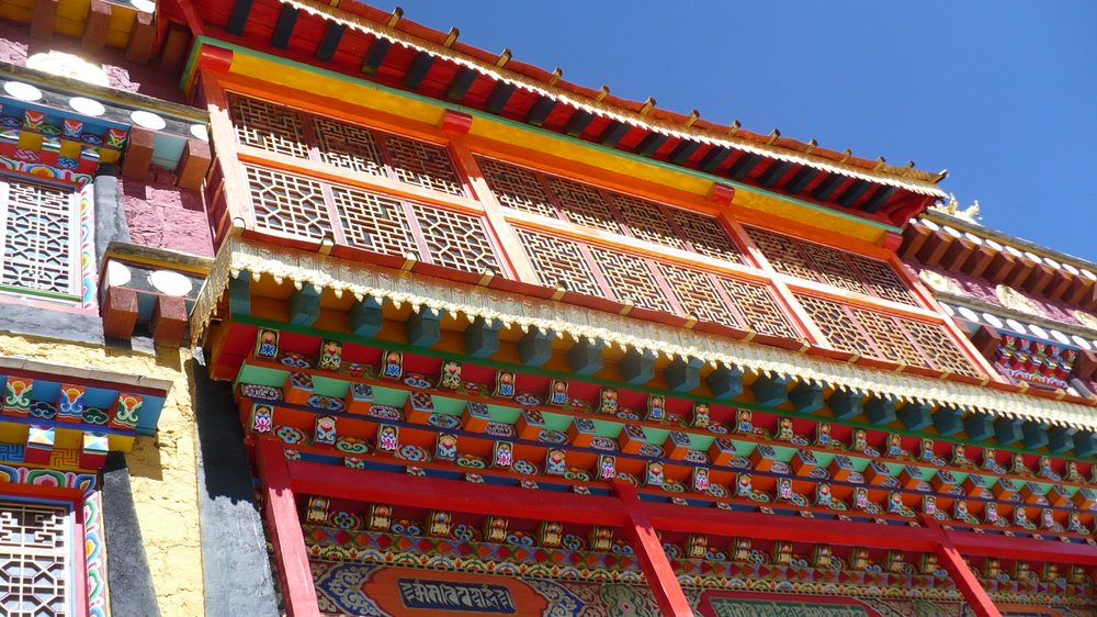 Magnificent gilded Tibetan roofs and white stupas of the Songzanlin Monastery complex in Shangri-La against blue sky