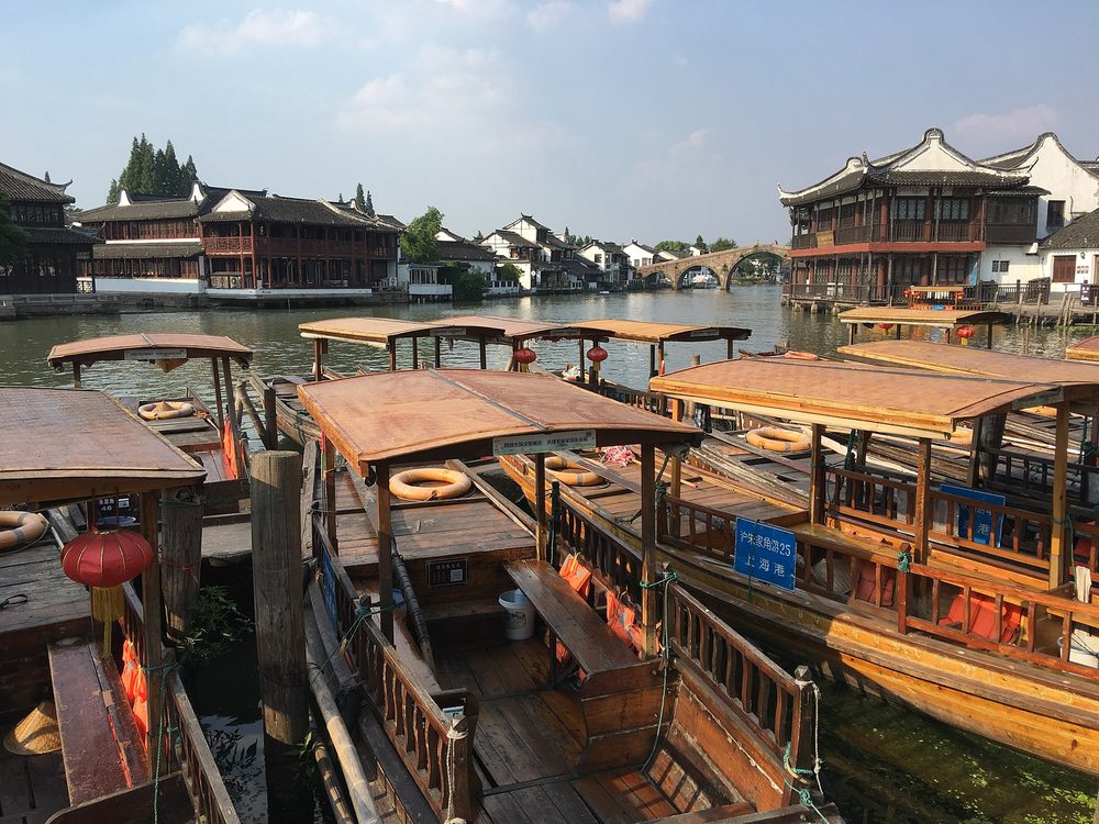 Traditional arched stone Fangsheng Bridge spanning the tranquil canal lined with willow trees and wooden boats in Zhujiajiao Water Town