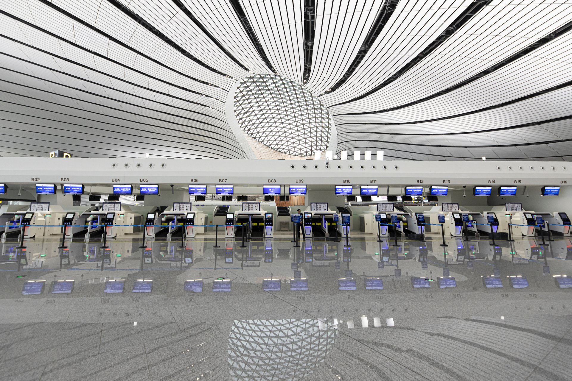 Automated airline check-in counters and baggage conveyor belts in modern Chinese airport terminal